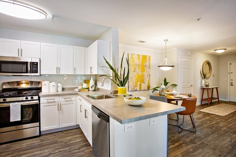 A modern kitchen with white cabinets and a wooden floor.