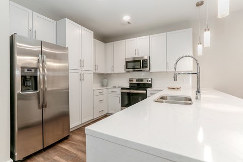 a white kitchen with stainless steel appliances and white counter tops