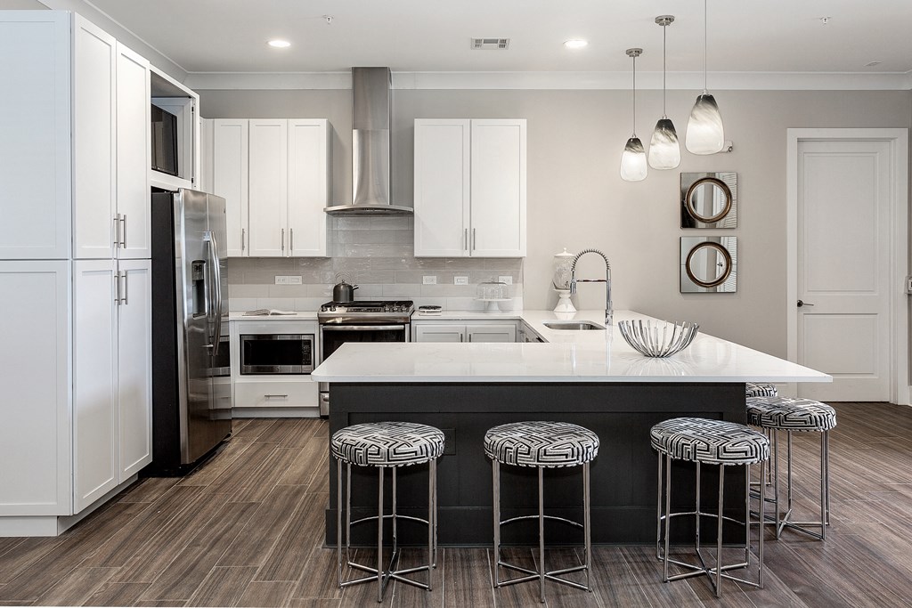 a kitchen with white cabinets and a large island with three stools at Annandale Apartment Homes, Murfreesboro, TN