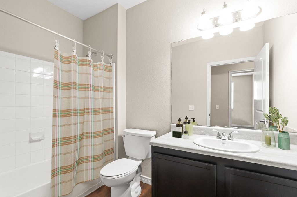 a bathroom with a white toilet next to a bathtub with a shower curtain