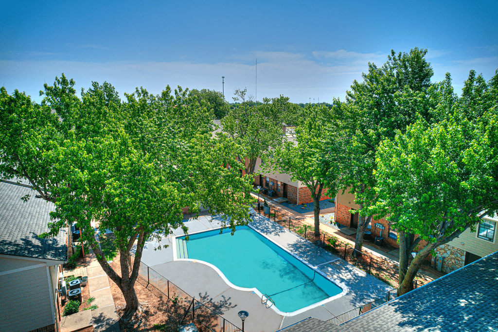an aerial view of a swimming pool with trees and a resort style pool