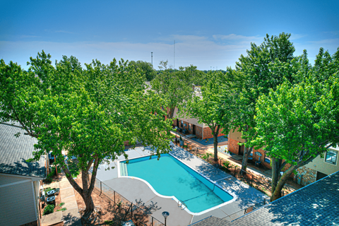 an aerial view of a swimming pool with trees and a resort style pool at Diamond Crest Townhomes, Norman, OK 73071