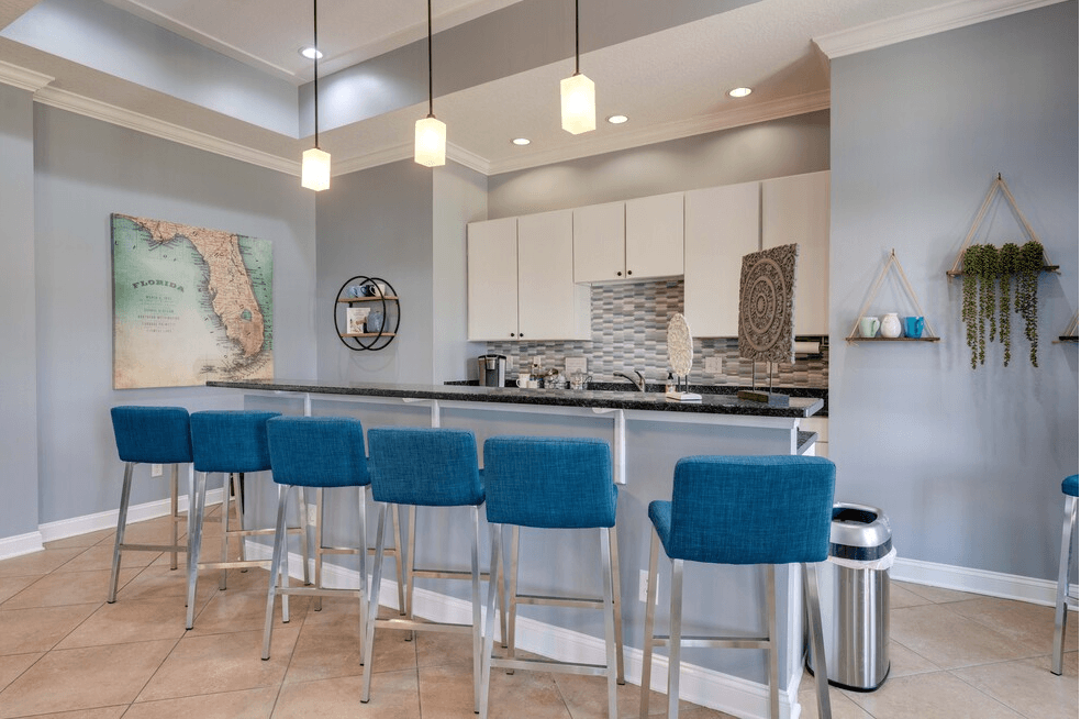a kitchen with a bar and stools in front of it at Magnolia Village Apartments, Jacksonville
