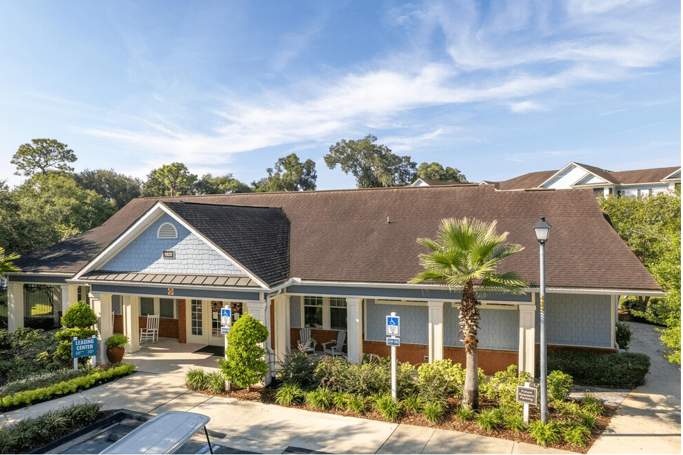 a building with a gray roof and palm trees in front of it at Magnolia Village Apartments, Jacksonville, Florida