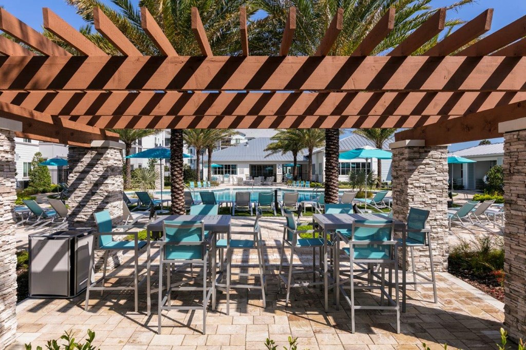 a covered patio with tables and chairs and a pool at Enclave at 3230 Apartments, South Daytona, 32119
