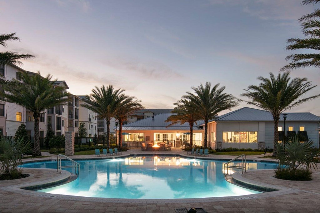 A swimming pool in front of a building with palm trees at Enclave at 3230 Apartments, South Daytona, Florida