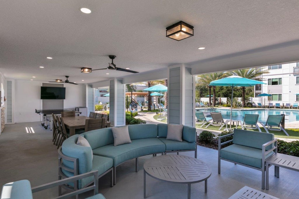 A patio with a blue couch and a table at Enclave at 3230 Apartments, South Daytona, FL