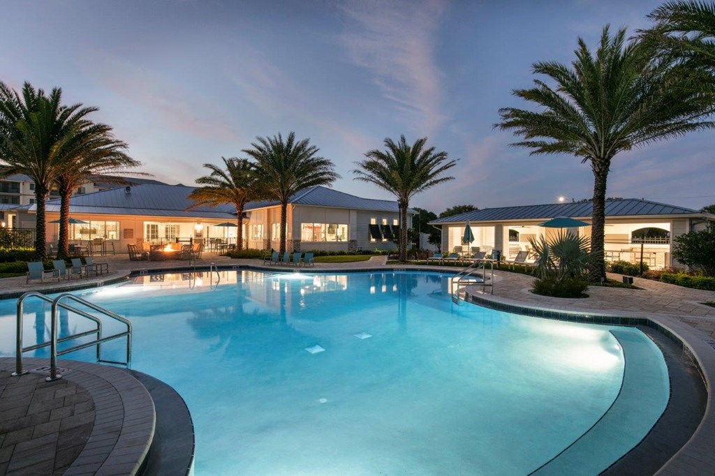 a large swimming pool with palm trees and a building in the background at Enclave at 3230 Apartments, South Daytona, Florida