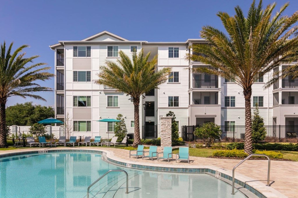 a building with palm trees next to a pool at Enclave at 3230 Apartments, Florida
