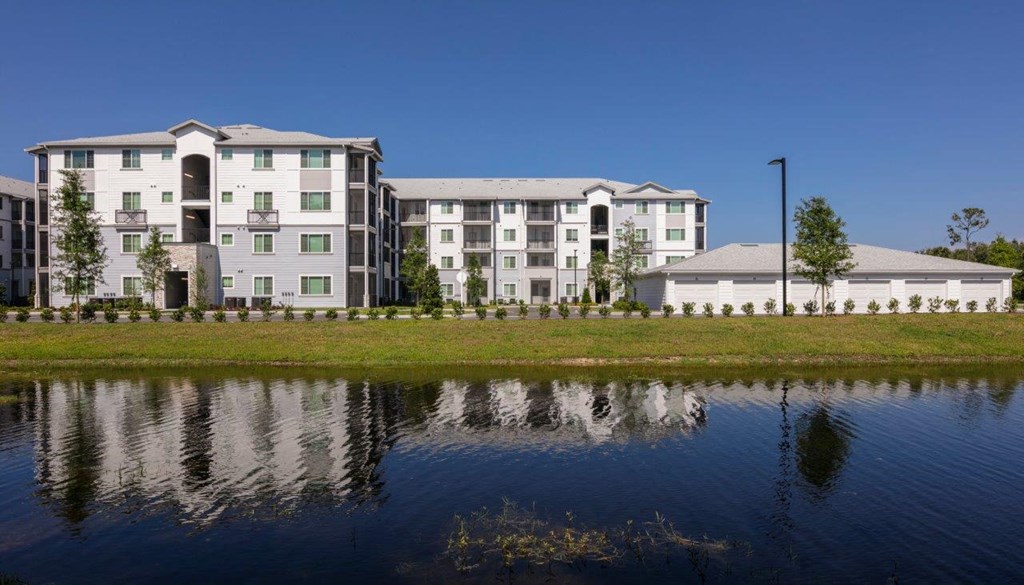 A large building with a pond in front of it at Enclave at 3230 Apartments, South Daytona, FL, 32119