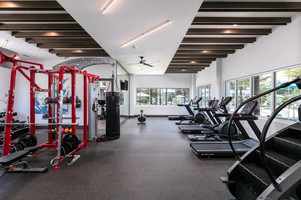 A gym with a variety of equipment including treadmills, weights, and a ceiling fan at Enclave at 3230 Apartments, South Daytona, FL