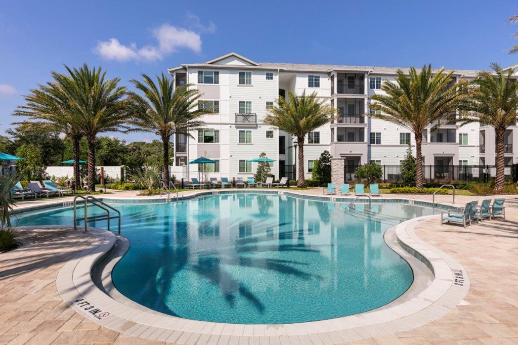 a large swimming pool with an apartment building in the background at Enclave at 3230 Apartments, South Daytona, Florida