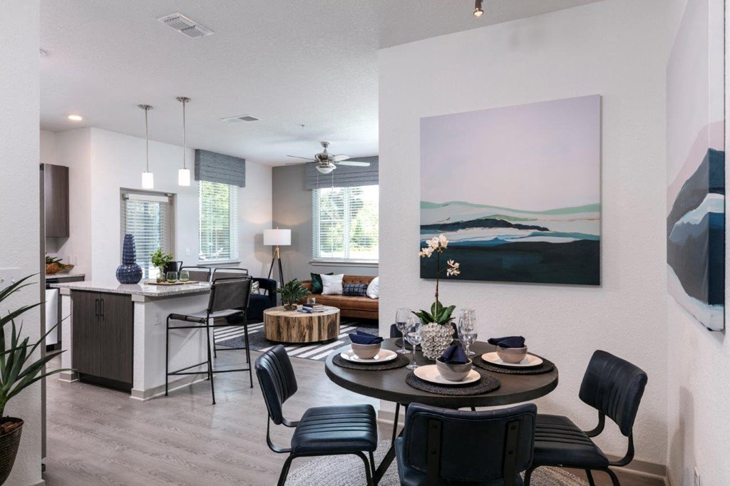 A dining room with a table set for four and a painting on the wall at Enclave at 3230 Apartments, Florida