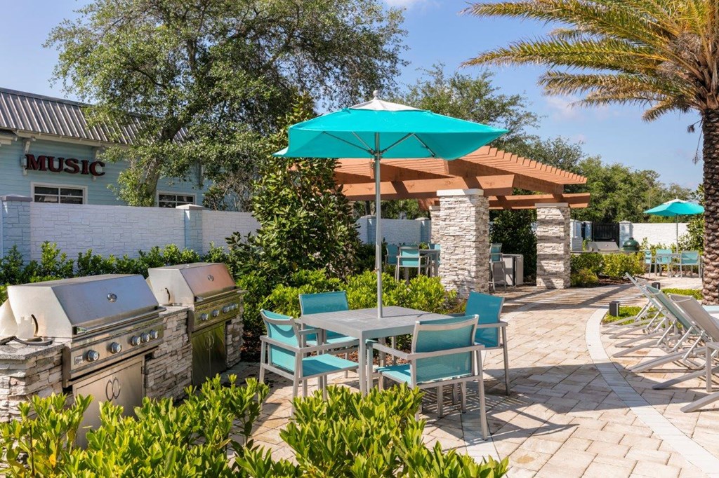 a patio with tables and chairs and a blue umbrella at Enclave at 3230 Apartments, South Daytona, 32119