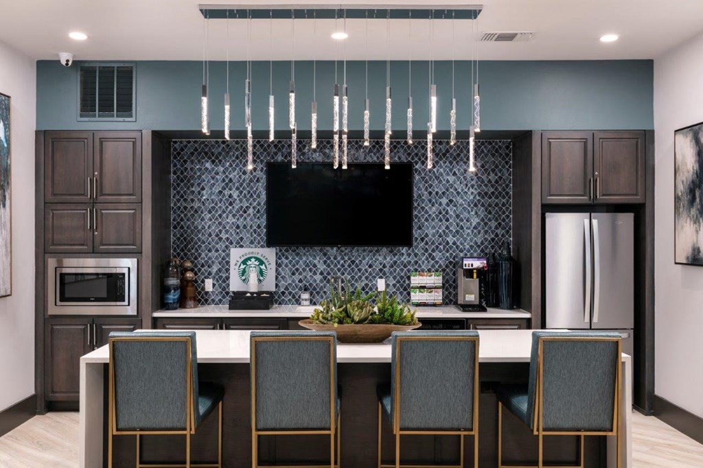 A modern kitchen with a dark blue backsplash and a large island with four chairs at Enclave at 3230 Apartments, Florida