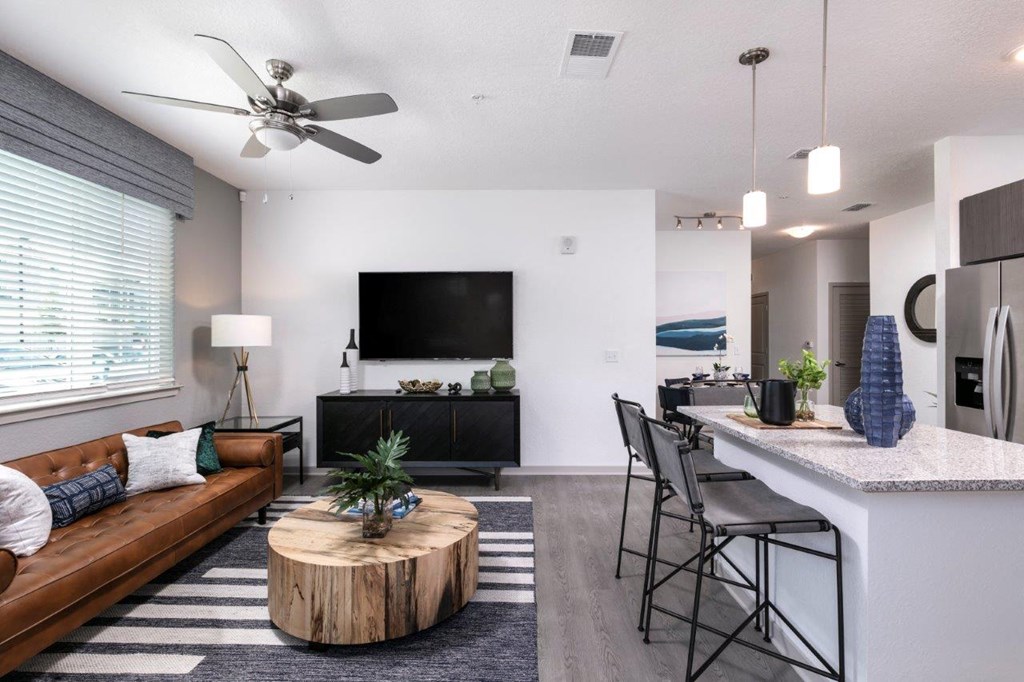 a living room and kitchen with a couch and a table at Enclave at 3230 Apartments, South Daytona, FL