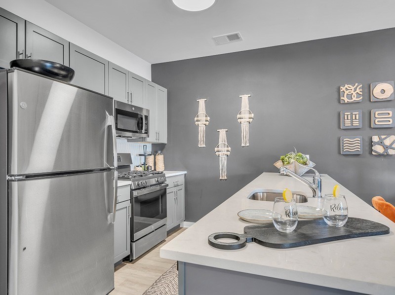 A modern kitchen with a stainless steel refrigerator and a white countertop.