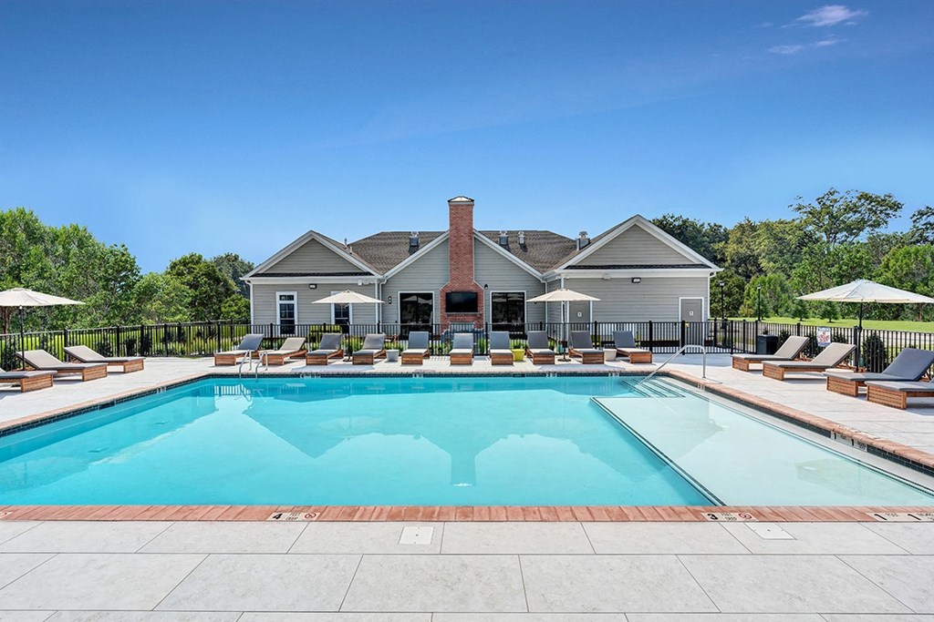A large swimming pool surrounded by lounge chairs and umbrellas.