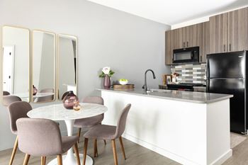 A kitchen with a white counter and brown chairs.