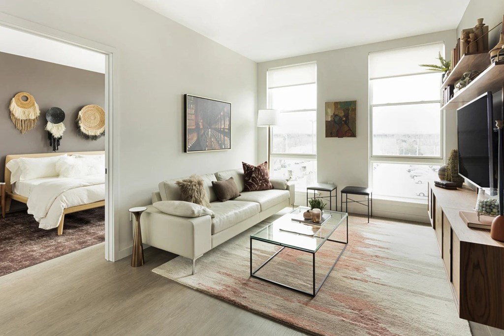 A living room with a white couch and a glass coffee table.