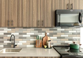 A kitchen with a sink, stove, and wooden cabinets.