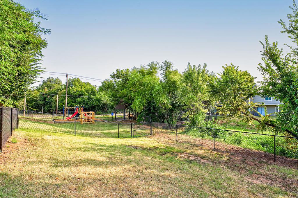 the yard is fenced in with a playground and trees at Diamond  Trail Apartments, Oklahoma City, OK
