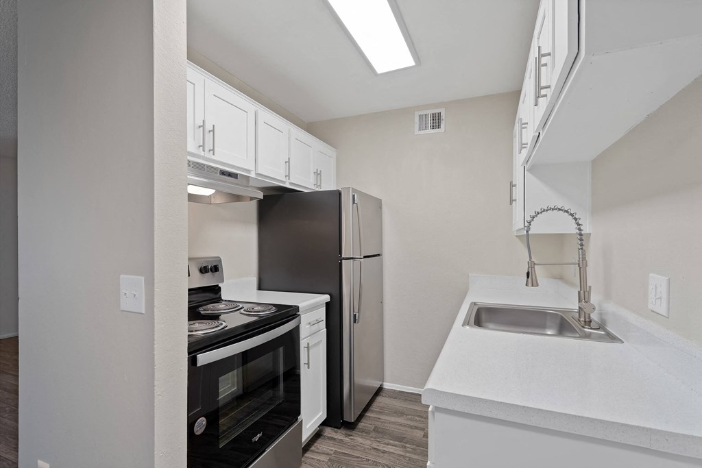 Kitchen with white cabinets and black appliances and a stainless steel refrigerator at Agave Apartments, Tucson, Arizona