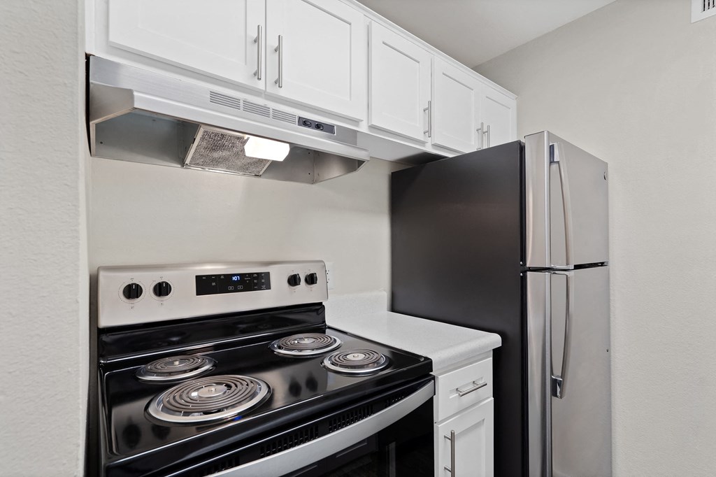 Kitchen with white cabinets and black appliances and a refrigerator at Agave Apartments, Tucson, AZ