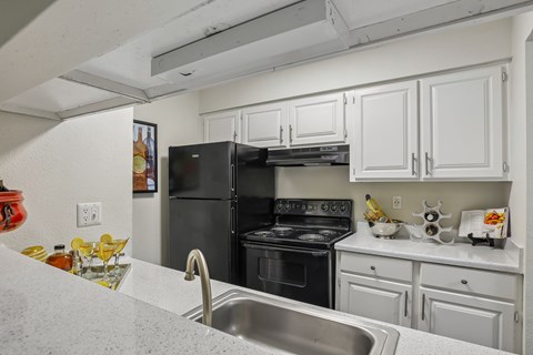 A kitchen with white cabinets and a black stove top oven.