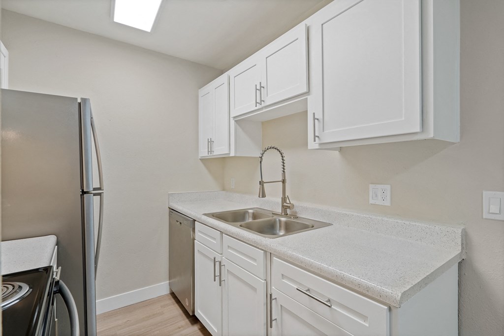 Kitchen with white cabinets and a sink and a refrigerator at Verde Apartments in Tucson.
