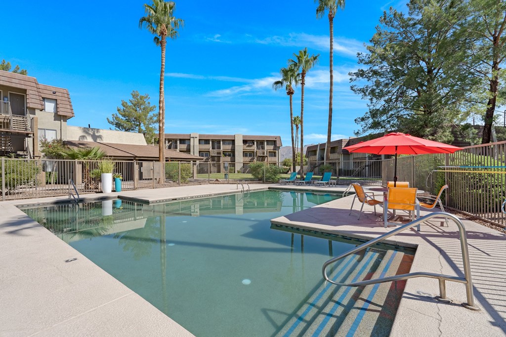 our apartments have a resort style pool with chairs and an umbrella in Tucson.