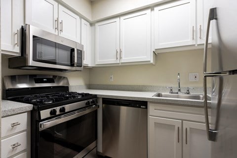 Kitchen with stainless steel appliances and white cabinets at Envue Apartments, Texas, 77802