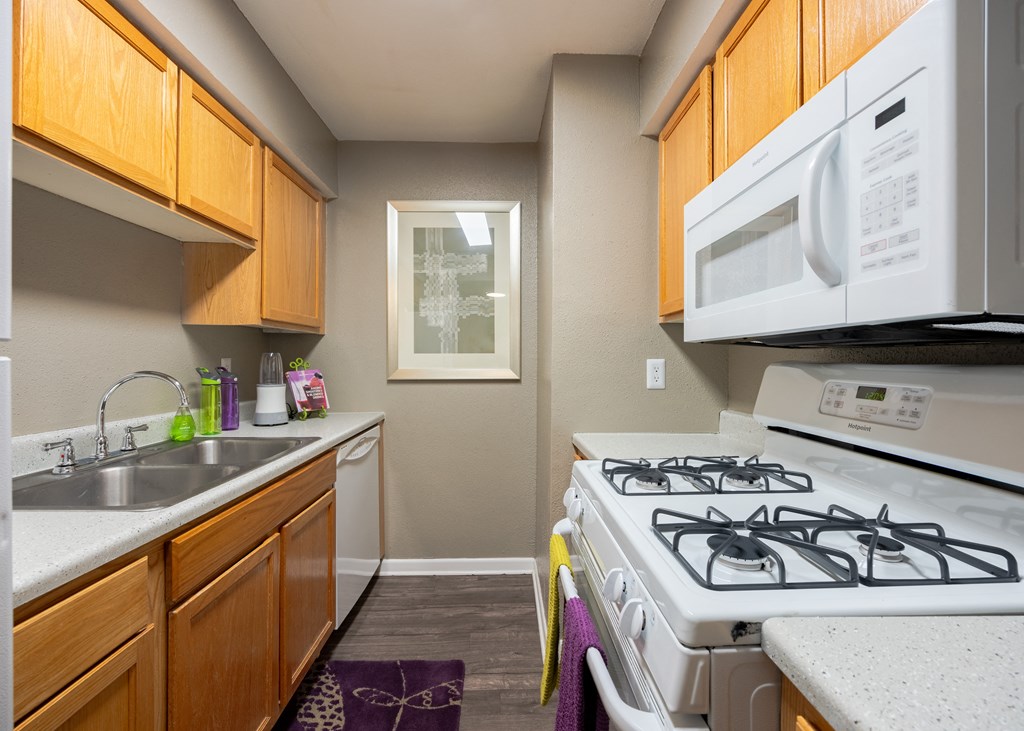 Kitchen with a white stove top oven next to a sink and a window at Envue Apartments, Bryan, TX, 77802