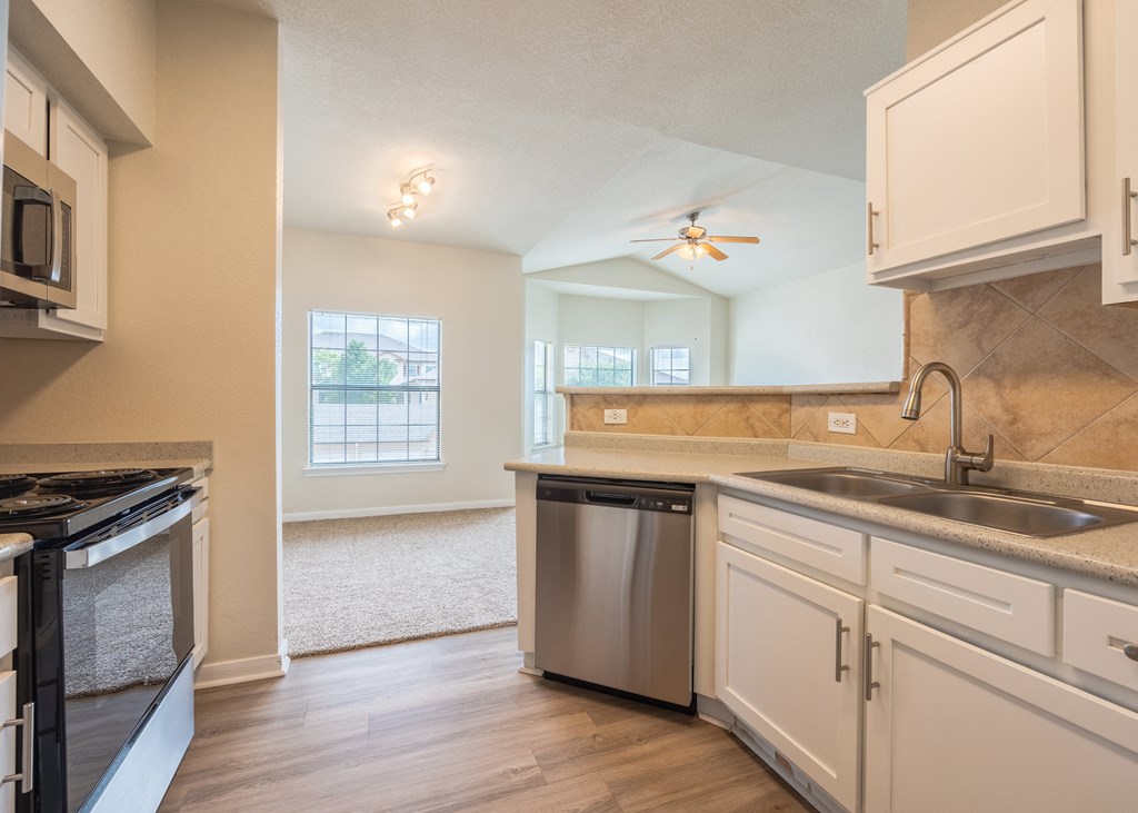 Kitchen with white cabinets and a stainless steel dishwasher at Park Hudson Place Apartments, Texas