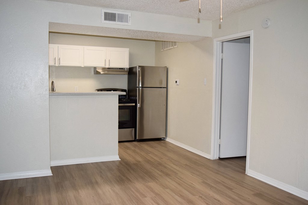 an empty apartment with a kitchen and a refrigerator at The Wick, College Station