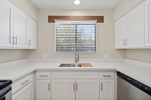 A kitchen with white cabinets and a window with blinds.at San Xavier Casitas, Tucson, AZ 85716