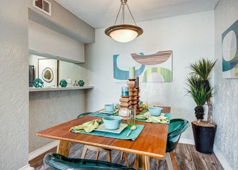 a dining area with a wooden table and green chairs at Sundance Apartments, College Station, TX