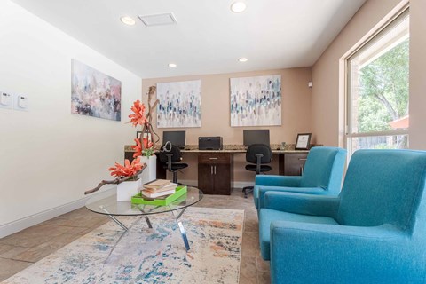 A living room with a blue chair and a glass table.