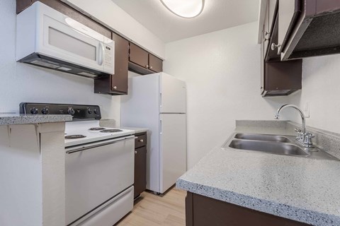 A kitchen with a stove, oven, refrigerator, and microwave.