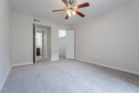 A room with a ceiling fan and carpeted floor.