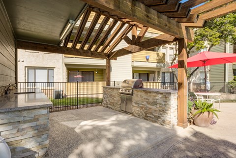 A patio with a stone wall and a wooden pergola.