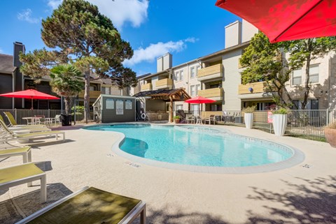 A pool surrounded by lounge chairs and umbrellas.