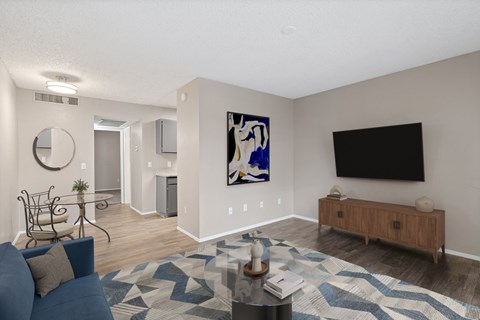 A living room with a blue couch and a painting on the wall.
