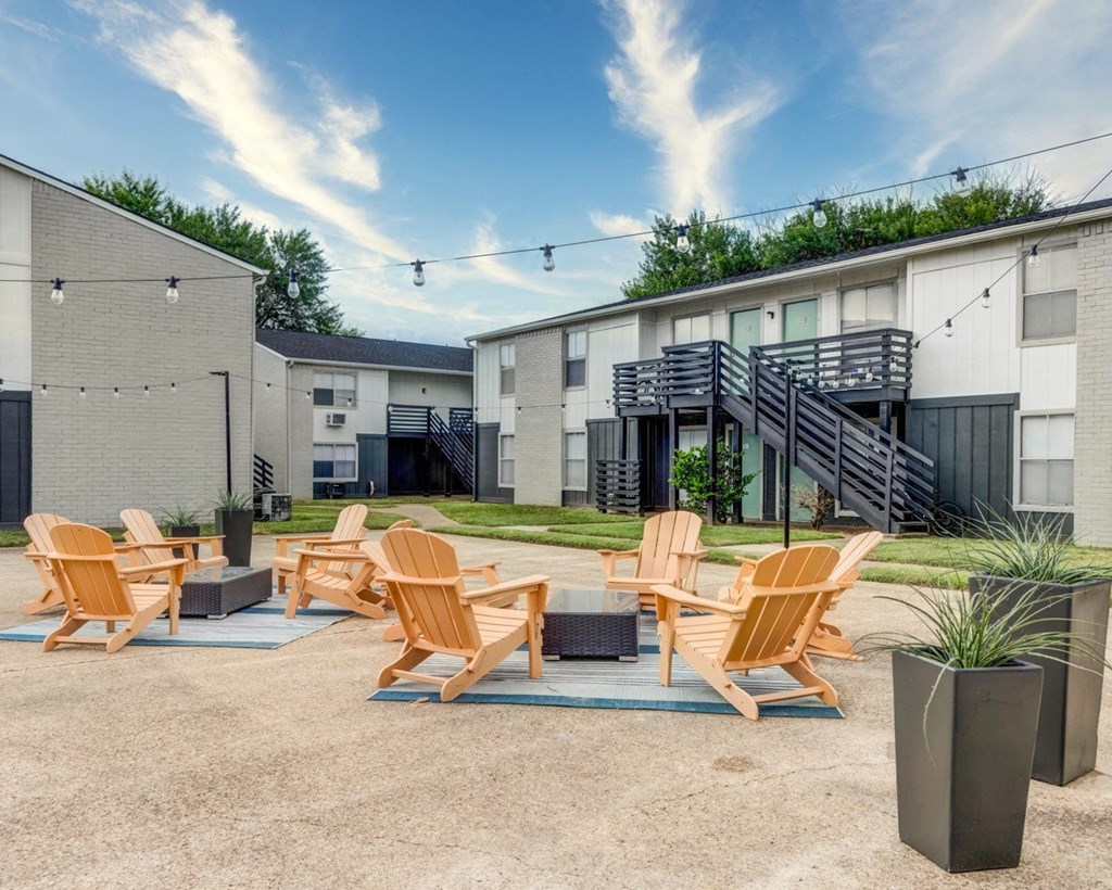 Patio with a fire pit and lounge chairs in front of an apartment building  at The Wick, College Station