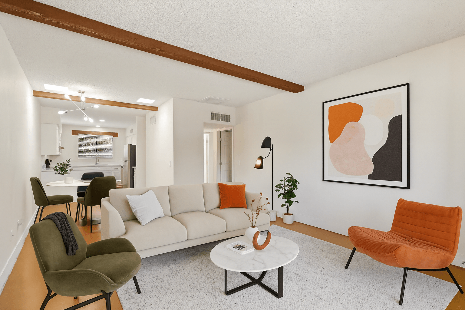 A living room with a white couch, orange chair, and a painting on the wall.