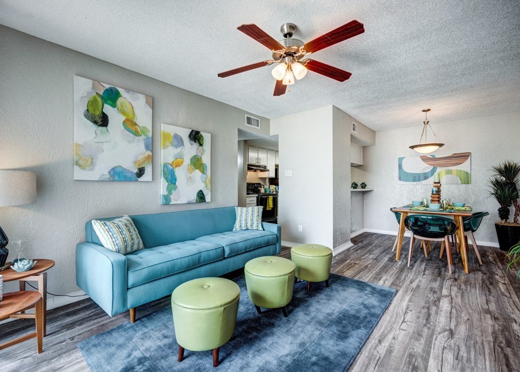 a living room with a blue couch and a ceiling fan at Sundance and Sausalito Apartments, College Station