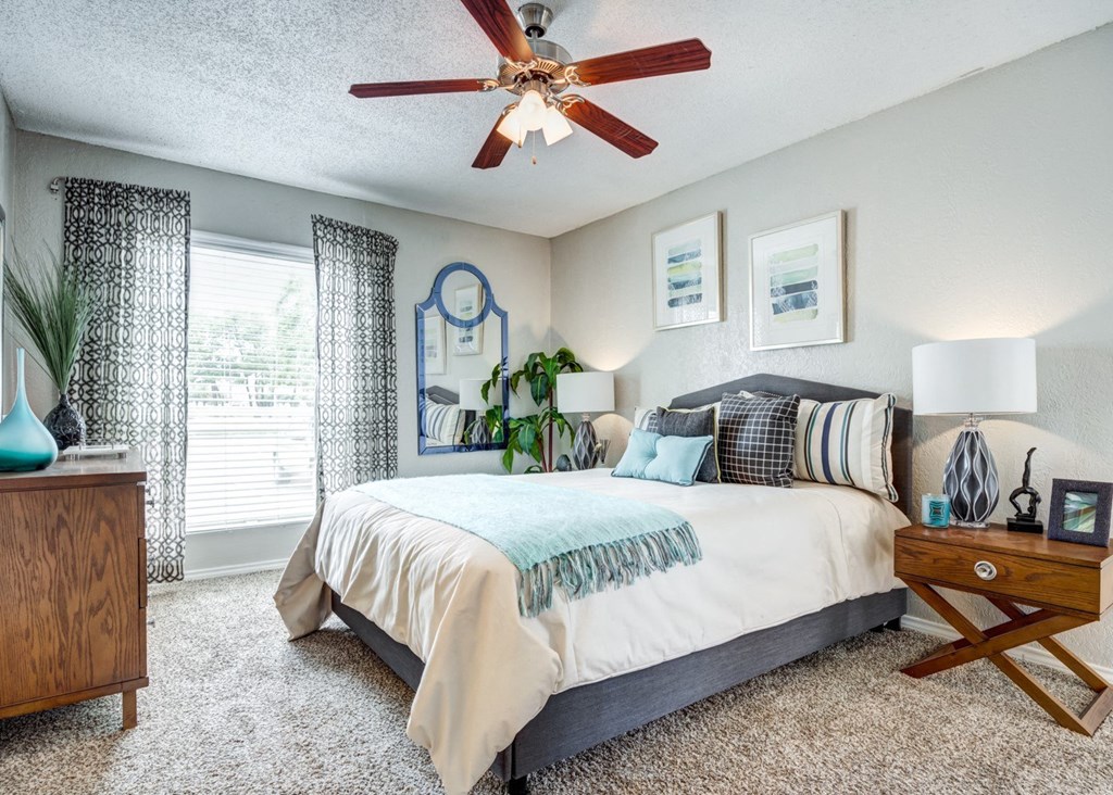a bedroom with a large bed and a ceiling fan at Sundance and Sausalito Apartments, College Station, TX