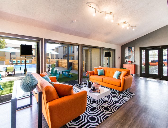 a living room with orange couches and a rug and sliding glass doors at Sundance and Sausalito Apartments, Texas, 77840