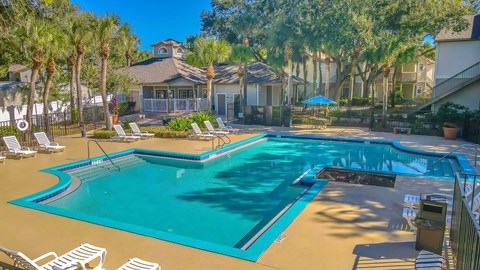 A large swimming pool surrounded by lounge chairs and palm trees.