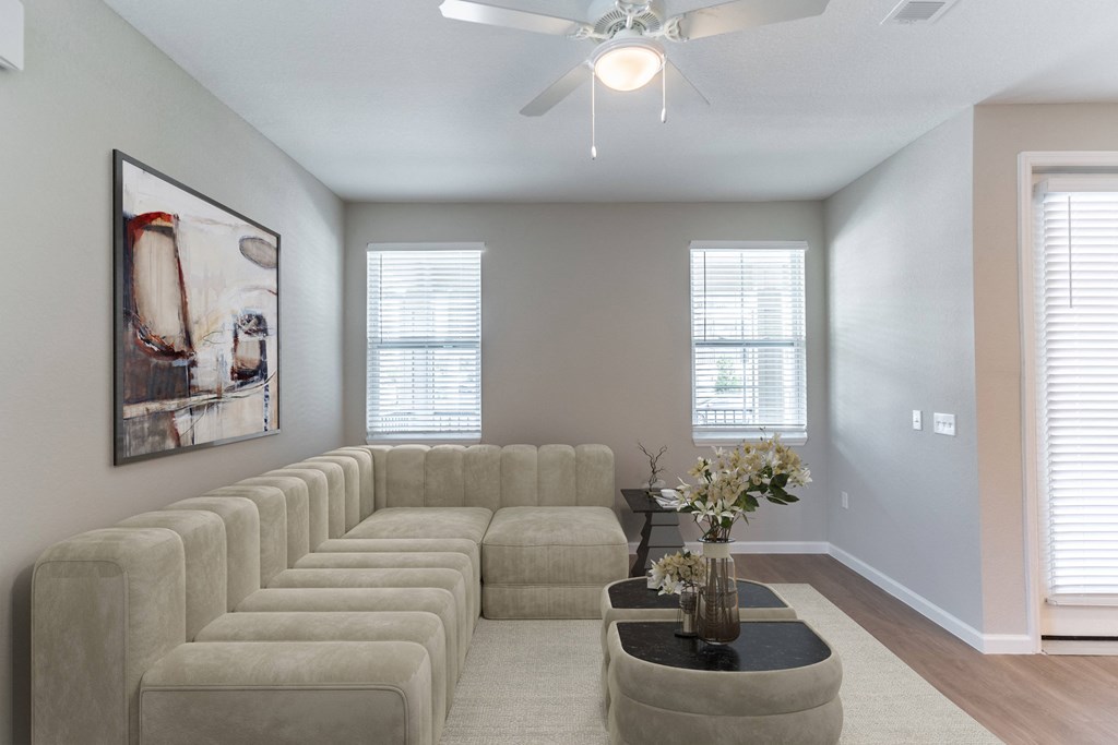 a living room with a large couch and a ceiling fan
